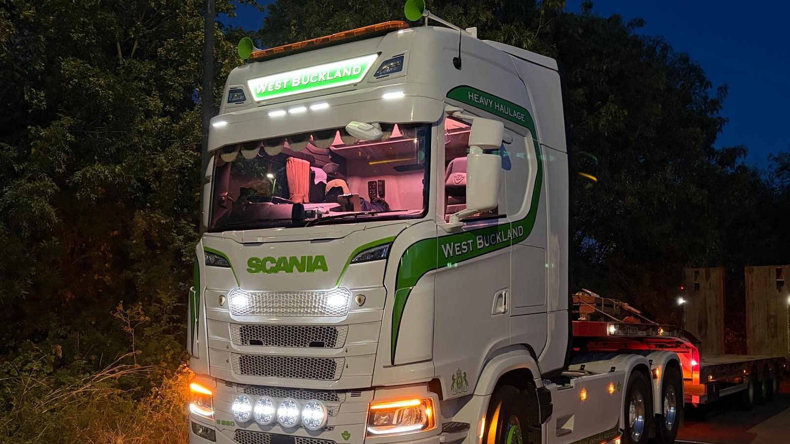 West Buckland Haulage Scania tractor unit and low loader lit up at the yard after dark